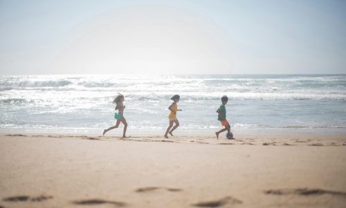 Children enjoying a fun day playing soccer at a sunny beach in Portugal. Perfect summer activity.